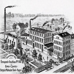 Historisches Schwarz-Weiß-Bild einer industriellen Anlage, die mehrere Gebäude mit rauchenden Schornsteinen zeigt. Im Vordergrund verläuft eine Straße mit Bäumen, und im Hintergrund sind weitere Gebäude sowie eine Landschaft mit Hügeln zu sehen. Unten links befindet sich ein Text mit Informationen zu einem Fernsprech-Anschluss und einem Giro-Konto der Bergisch Märkischen Bank in Hagen.