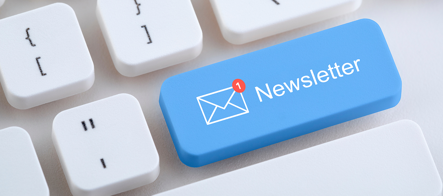 Ein blauer Tastaturknopf mit der Aufschrift "Newsletter" und einem roten Benachrichtigungspunkt, der auf einen neuen Newsletter hinweist. Der Hintergrund zeigt eine helle Taschen- und Tastaturstruktur.