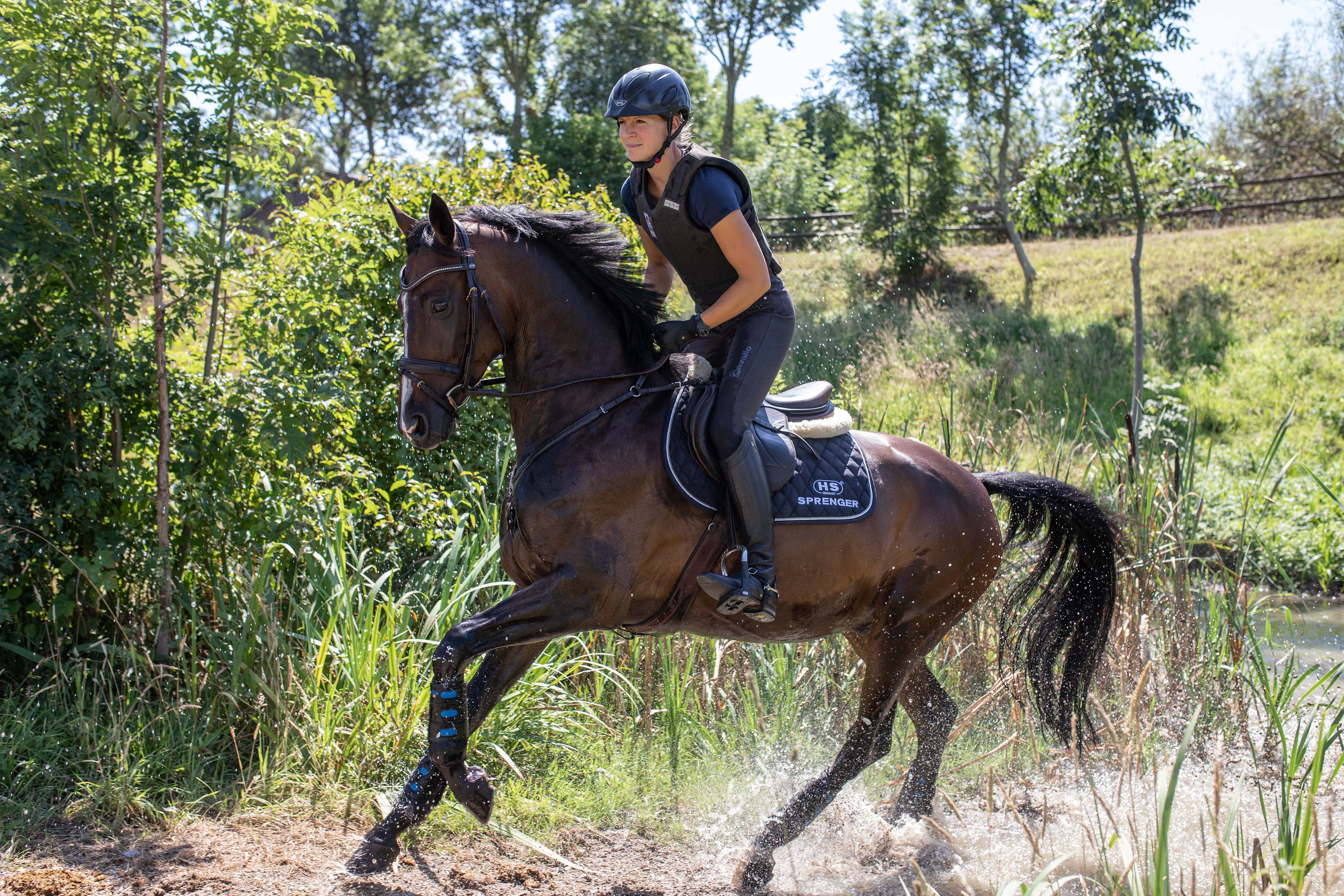 Reiterin mit Pferd reitet durchs Gelände