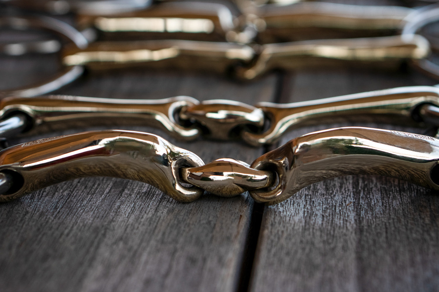 Nahaufnahme einer glänzenden Metallkette, die aus mehreren miteinander verbundenen Gliedern besteht. Die Kette liegt auf einer hölzernen Oberfläche, die ihre Textur und Farbe gut zur Geltung bringt. Die Lichtreflexionen auf dem Metall verstärken den visuellen Eindruck der Kette und betonen ihre glänzende Oberfläche.