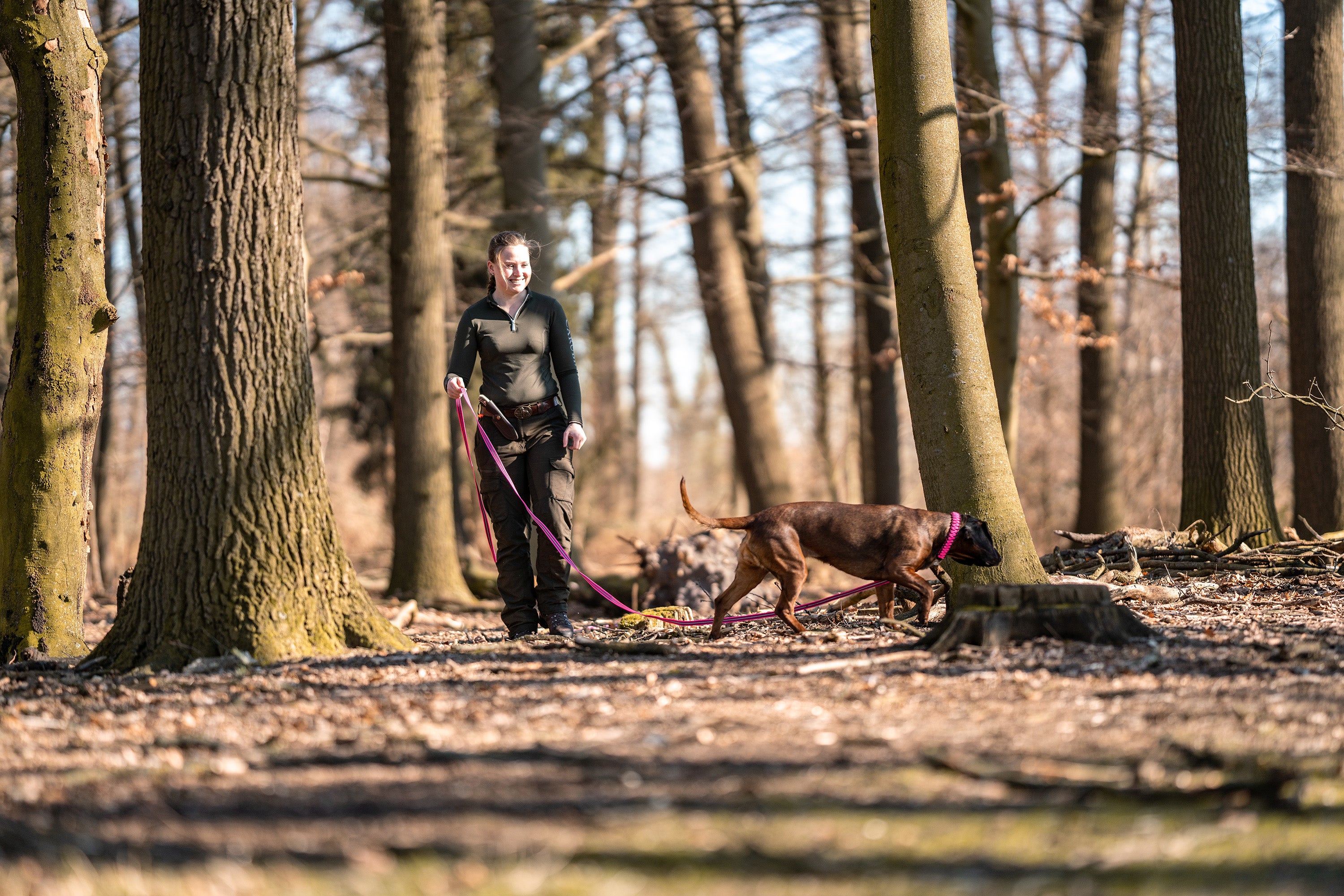 Frau mit Hund im Wald an pinker Schleppleine